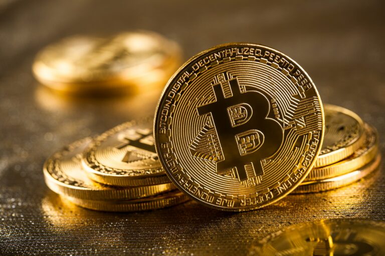 Gold bitcoins on glittering background, close up